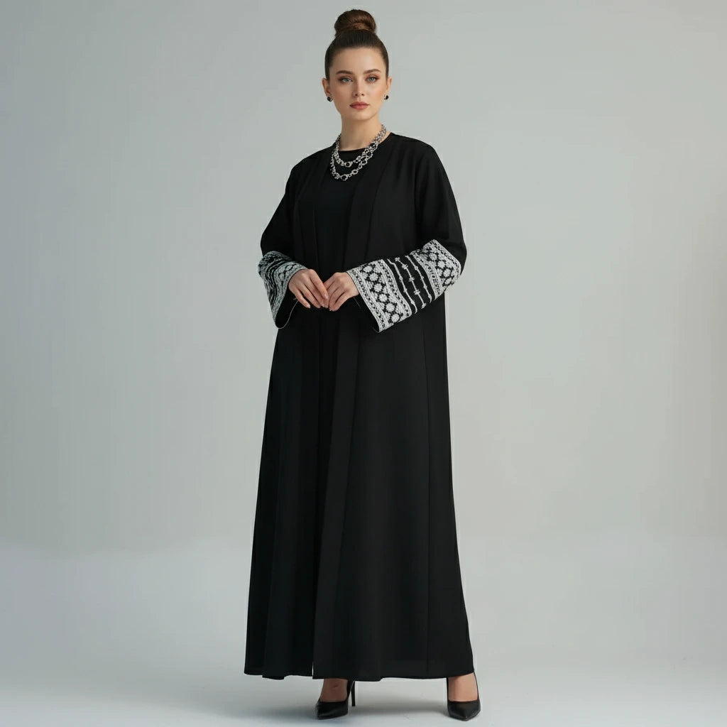 Black abaya with white embroidery on sleeves against a white background