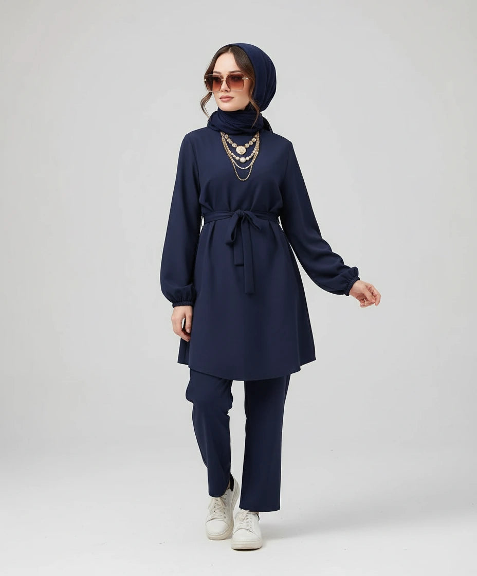 Woman wearing a navy blue outfit with a hijab on a white background