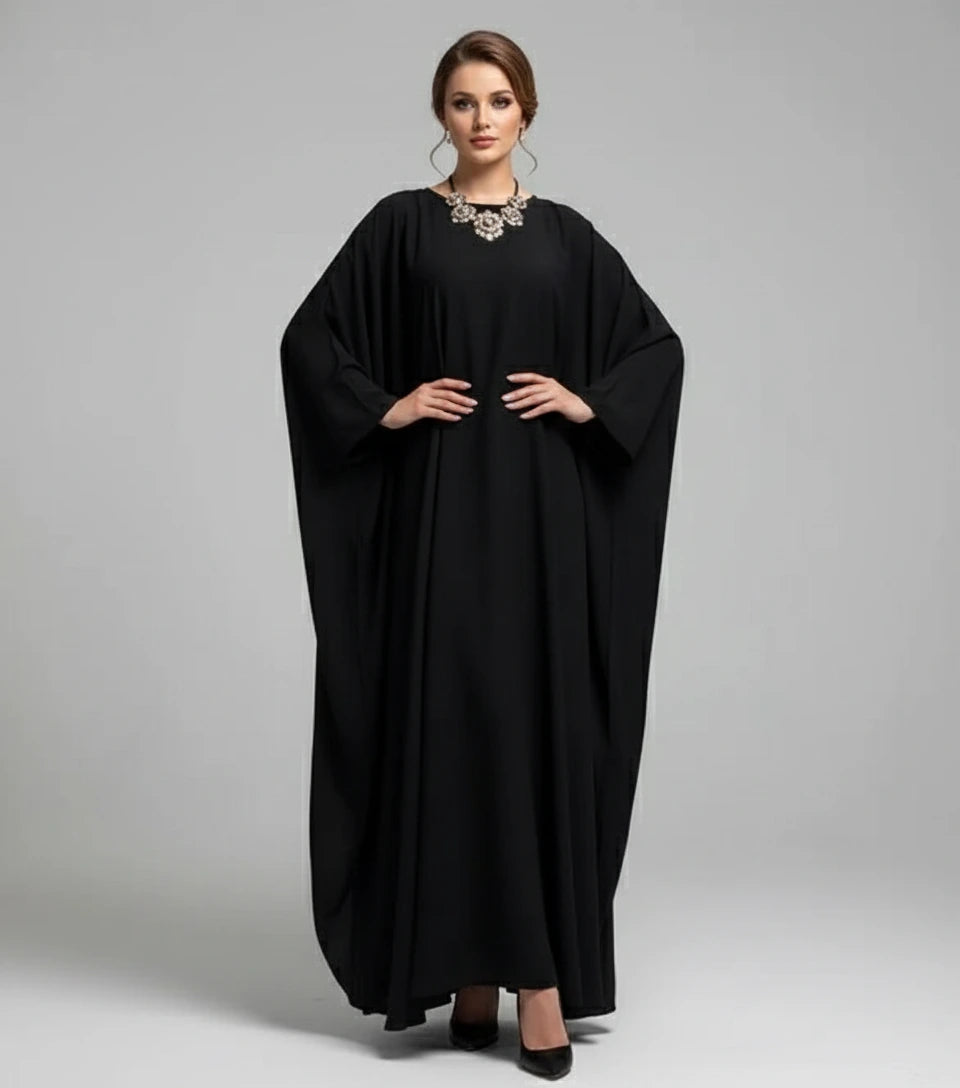 Woman wearing a black abaya on a gray background