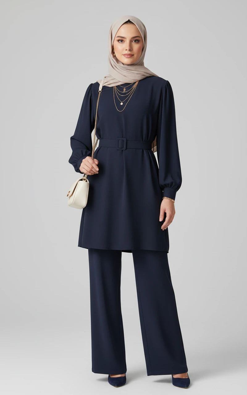 Woman wearing a navy blue outfit with a hijab on a gray background