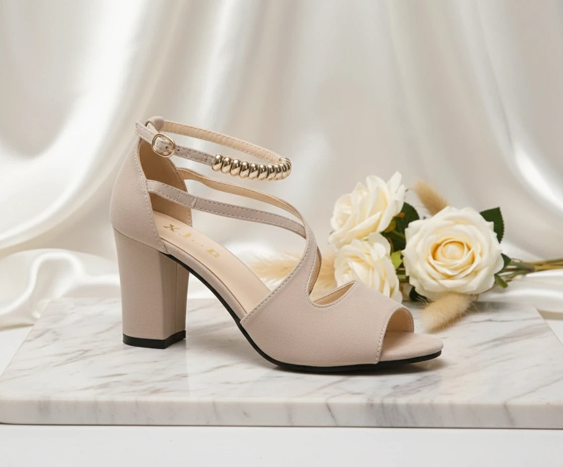 Beige high-heeled shoe with floral design on a marble surface with white roses.