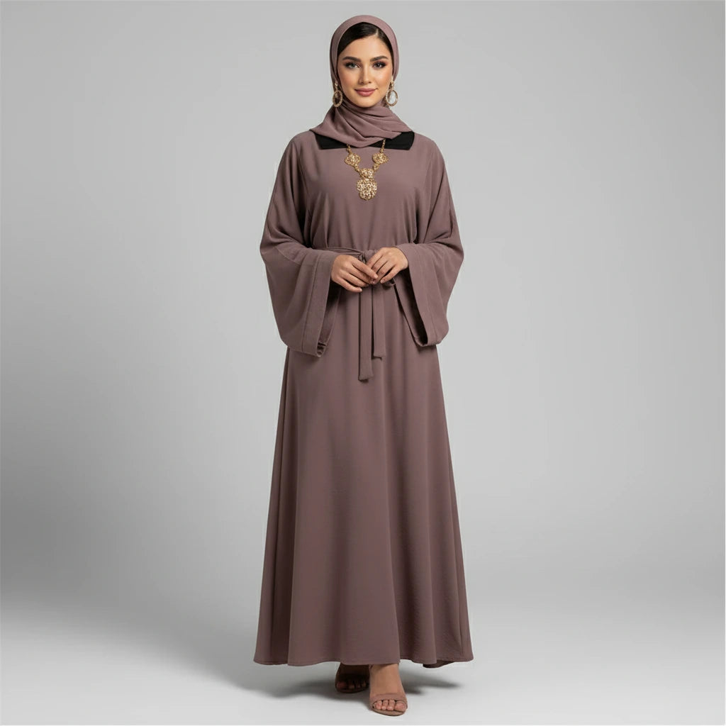 Brown dress worn by a person standing in a room with a white chair and decorative vase.