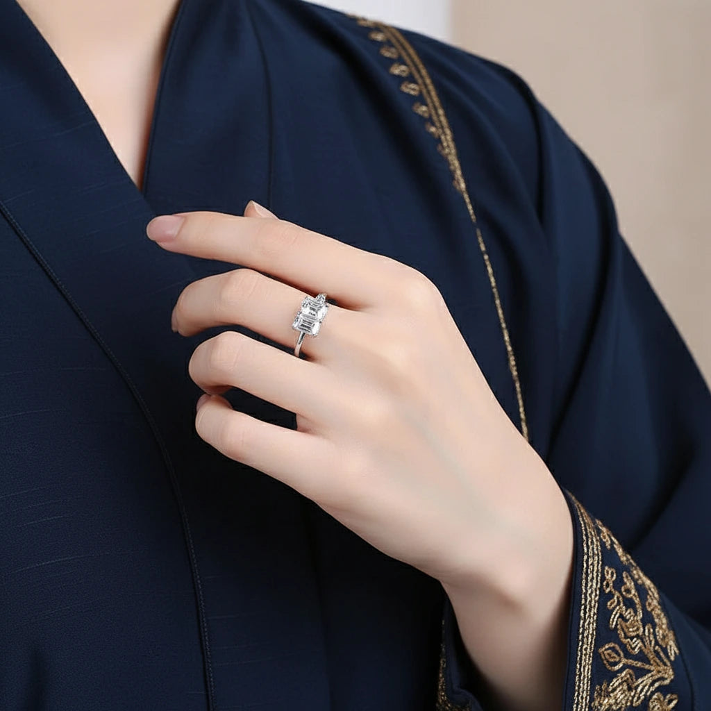 Hand wearing a diamond ring with a dark blue garment background