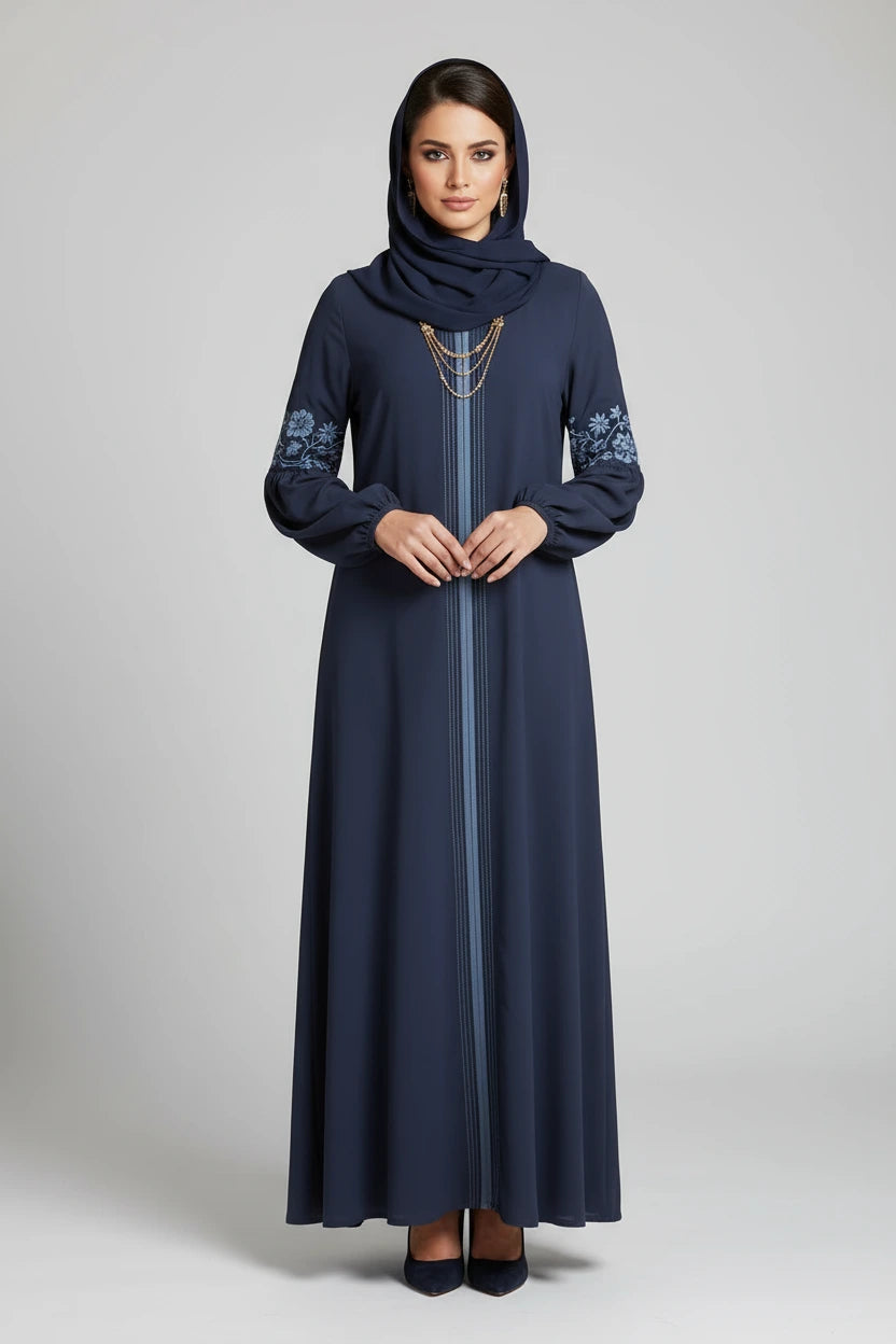 Woman wearing a long dark blue dress with floral patterns on a stone wall background