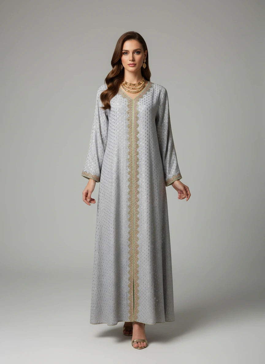 Long, light gray dress with gold trim on a mannequin against a white paneled wall.