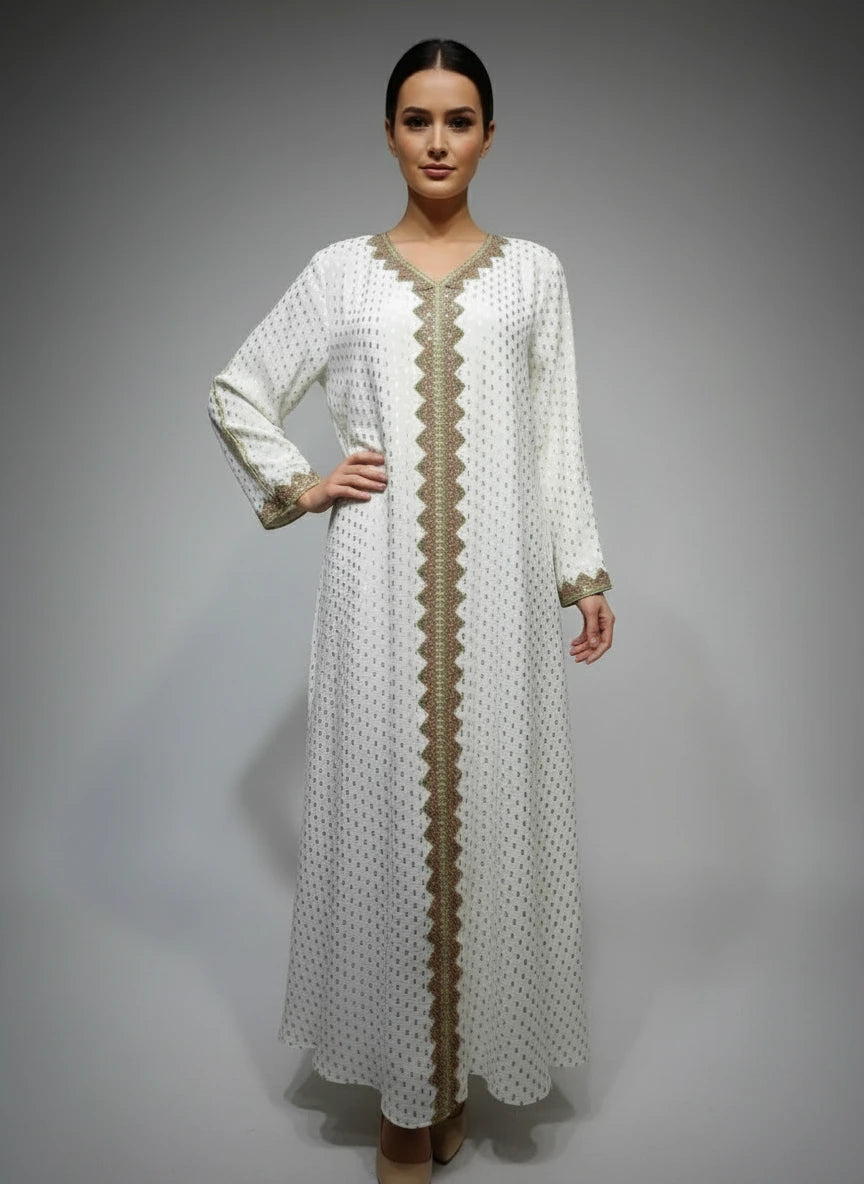 Long white dress with gold embroidery on a mannequin against a gray wall.